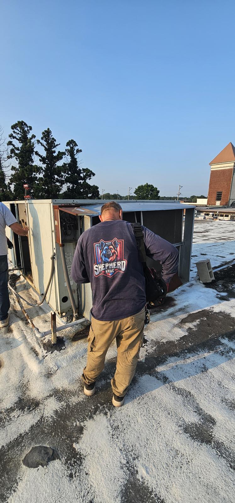Shepherd HVAC technician walking a commercial roof to a packaged unit
