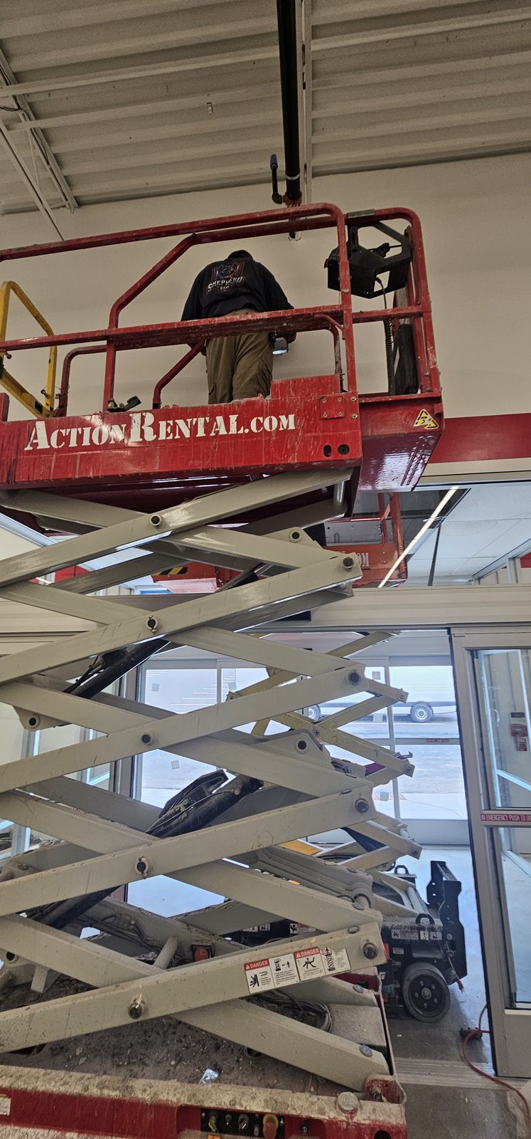 Shepherd HVAC technician working overhead on commercial ductwork from a lift