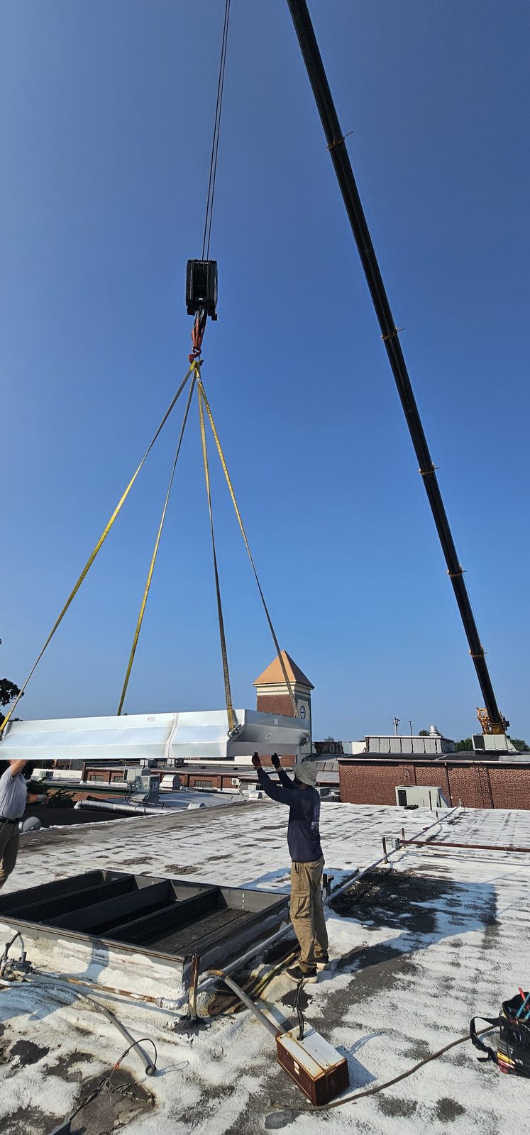 Shepherd HVAC technician guiding a crane pick during a rooftop unit replacement