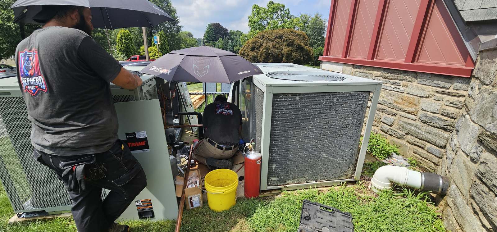 Shepherd HVAC technician servicing an outdoor condensing unit beside a home