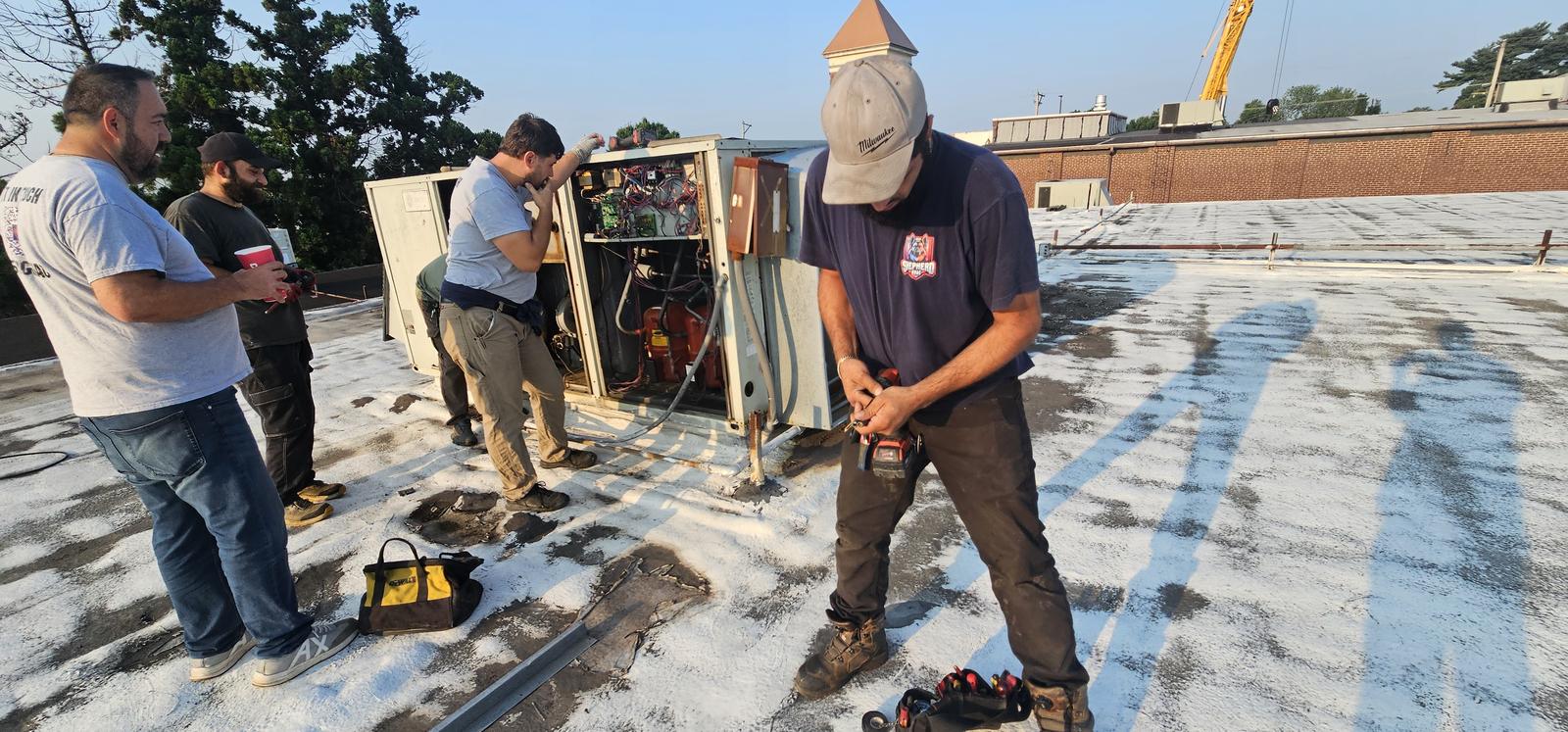 Shepherd HVAC crew inspecting an open rooftop unit on a commercial building
