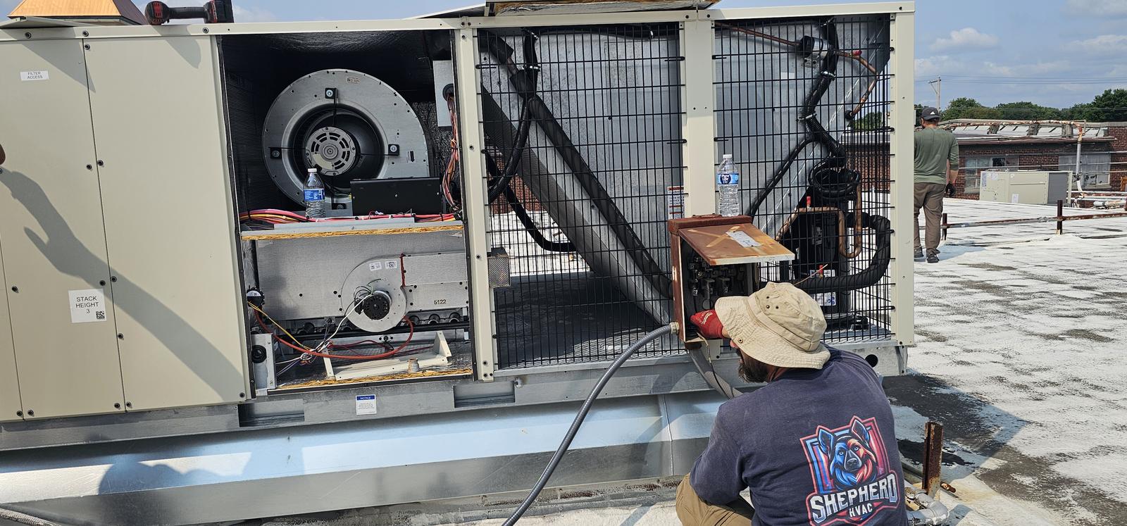Shepherd HVAC technician servicing the heating section and blower inside a rooftop unit