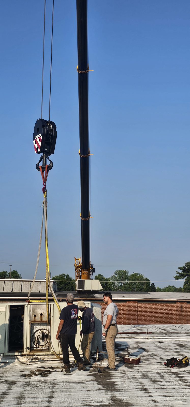 Crane boom lowering rigging to the roof during a rooftop HVAC changeout