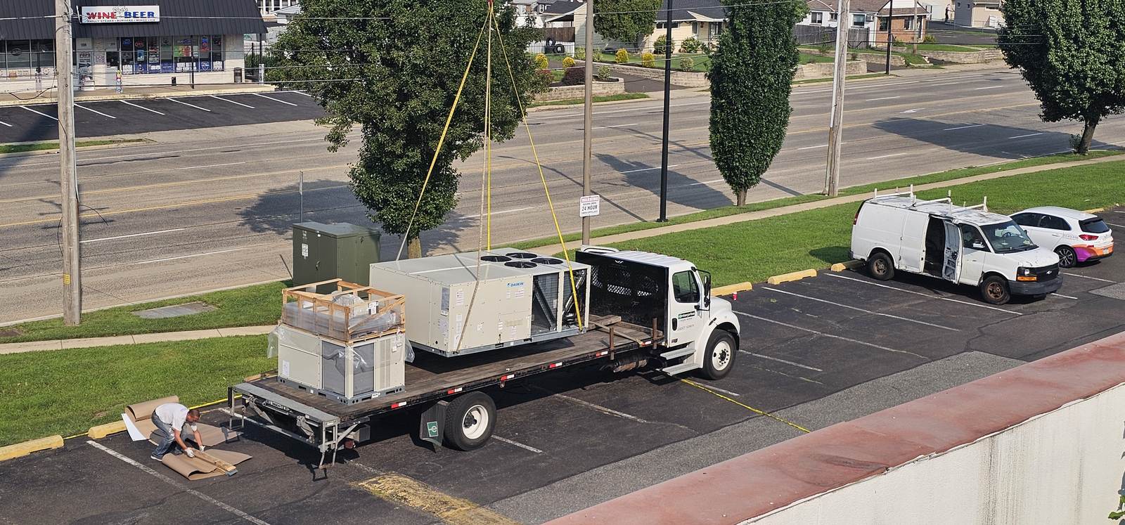 New rooftop HVAC units staged on a delivery trailer outside a commercial building